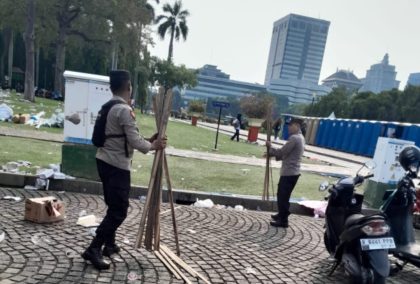 Polisi Bantu Petugas Kebersihan Bersihkan Monas Usai Aksi Buruh